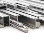 A collection of metal bars, beams, and rods of various shapes and sizes, including I-beams, square tubes, and rebar—ideal for custom metal fabrication—arranged in a pile on a white background.